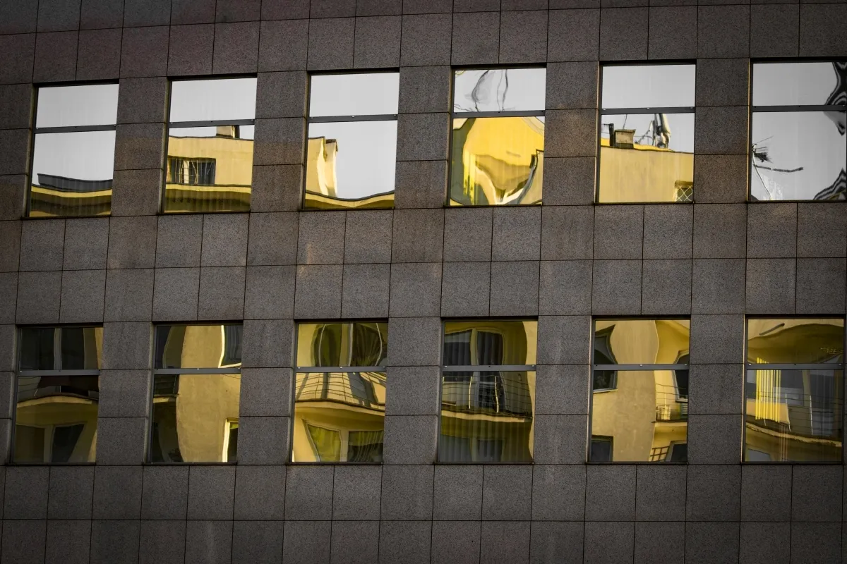 Row of lit windows mirrored in a dark building facade